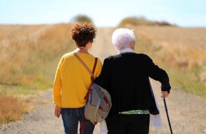 Alte und junge Frau Arm in Arm auf einem Feldweg